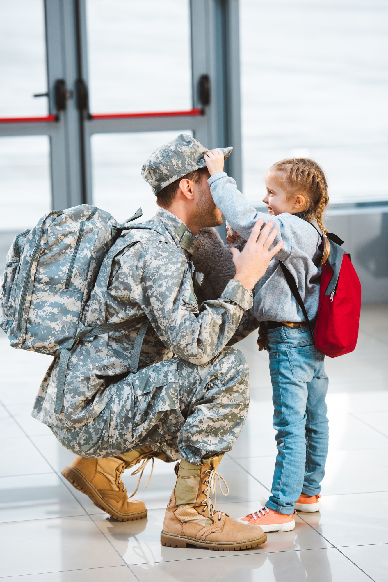 cute daughter touching cap of father in military uniform