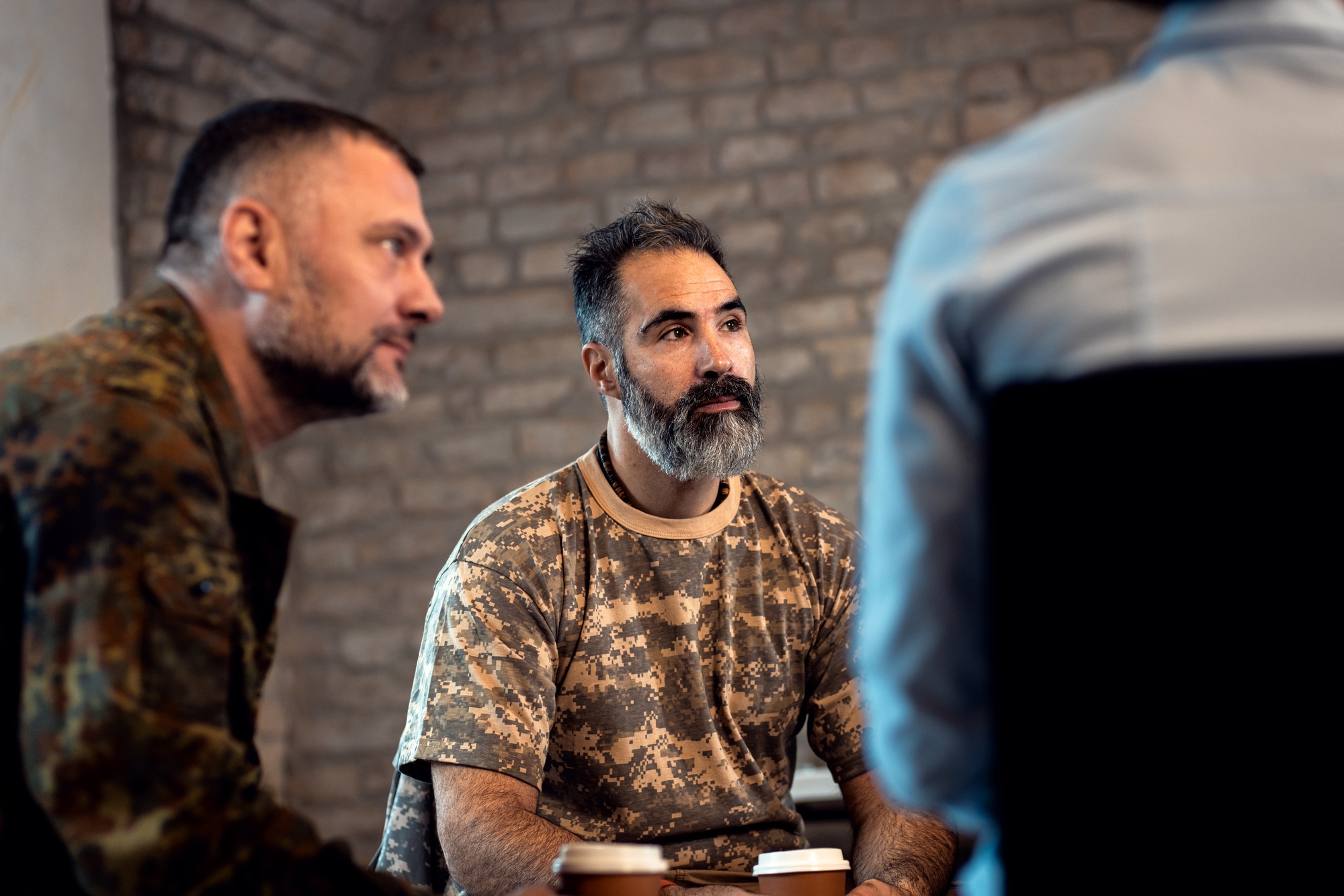 Group of diverse veterans talking during PTSD support group.