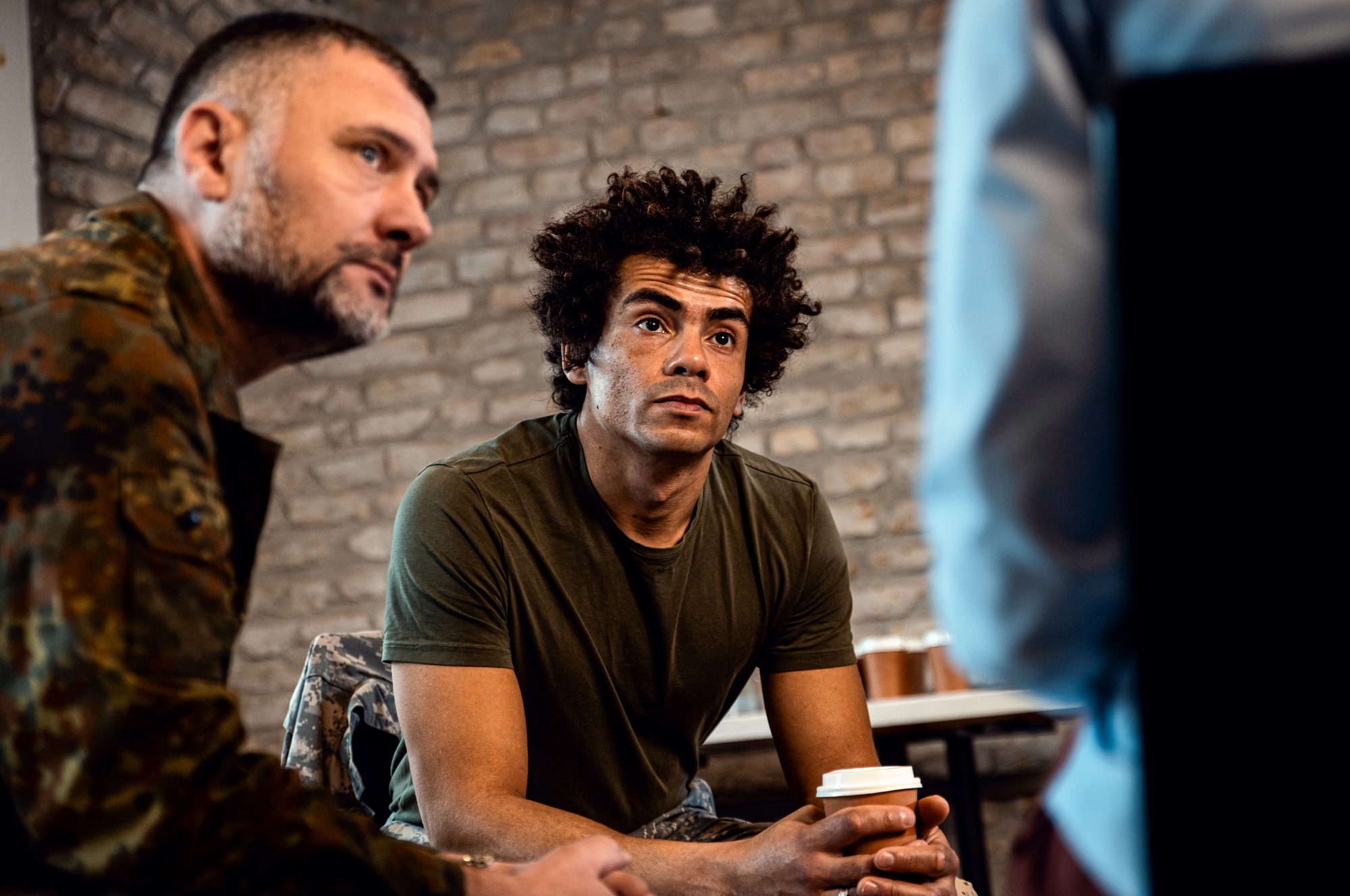 Group of diverse veterans talking during PTSD support group.